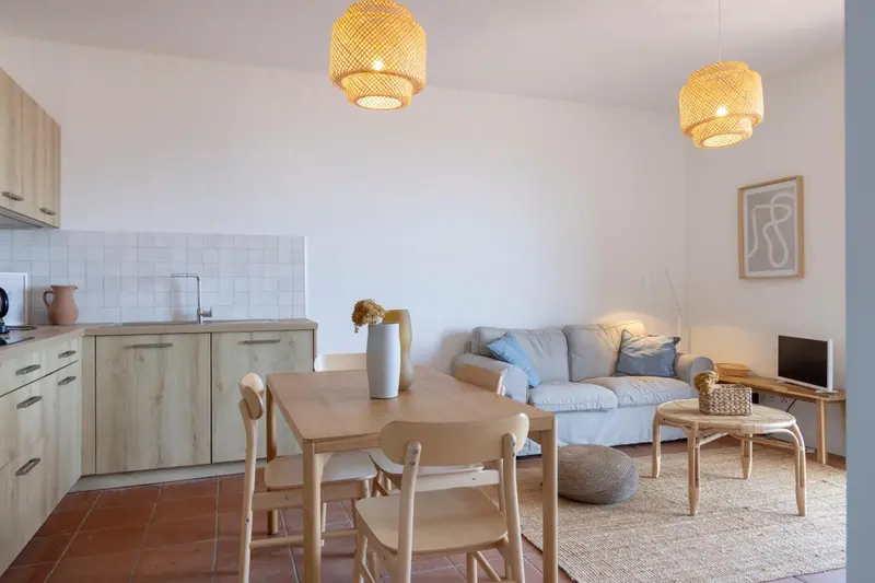 Espace de vie lumineux avec coin repas et canapé gris.