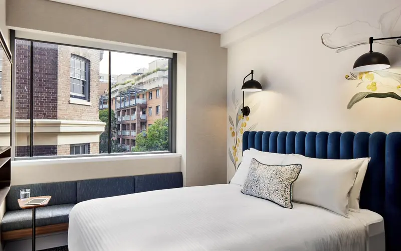 Une chambre lumineuse avec un grand lit et une vue sur la ville.