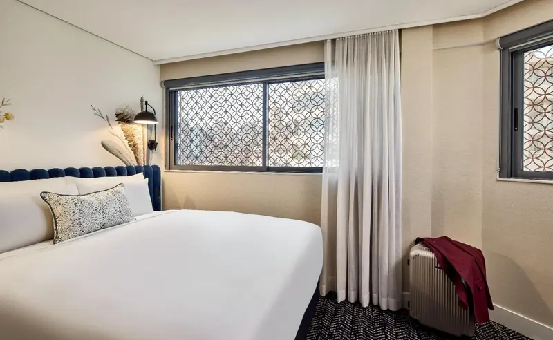 Une chambre lumineuse avec un grand lit recouvert d'une couette blanche.
