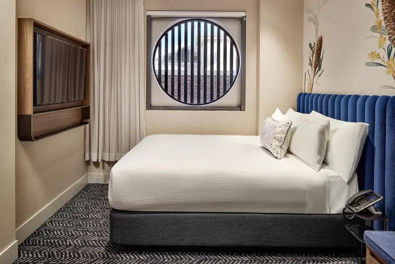 Une chambre avec un grand lit recouvert d'une courtepointe blanche et de coussins.