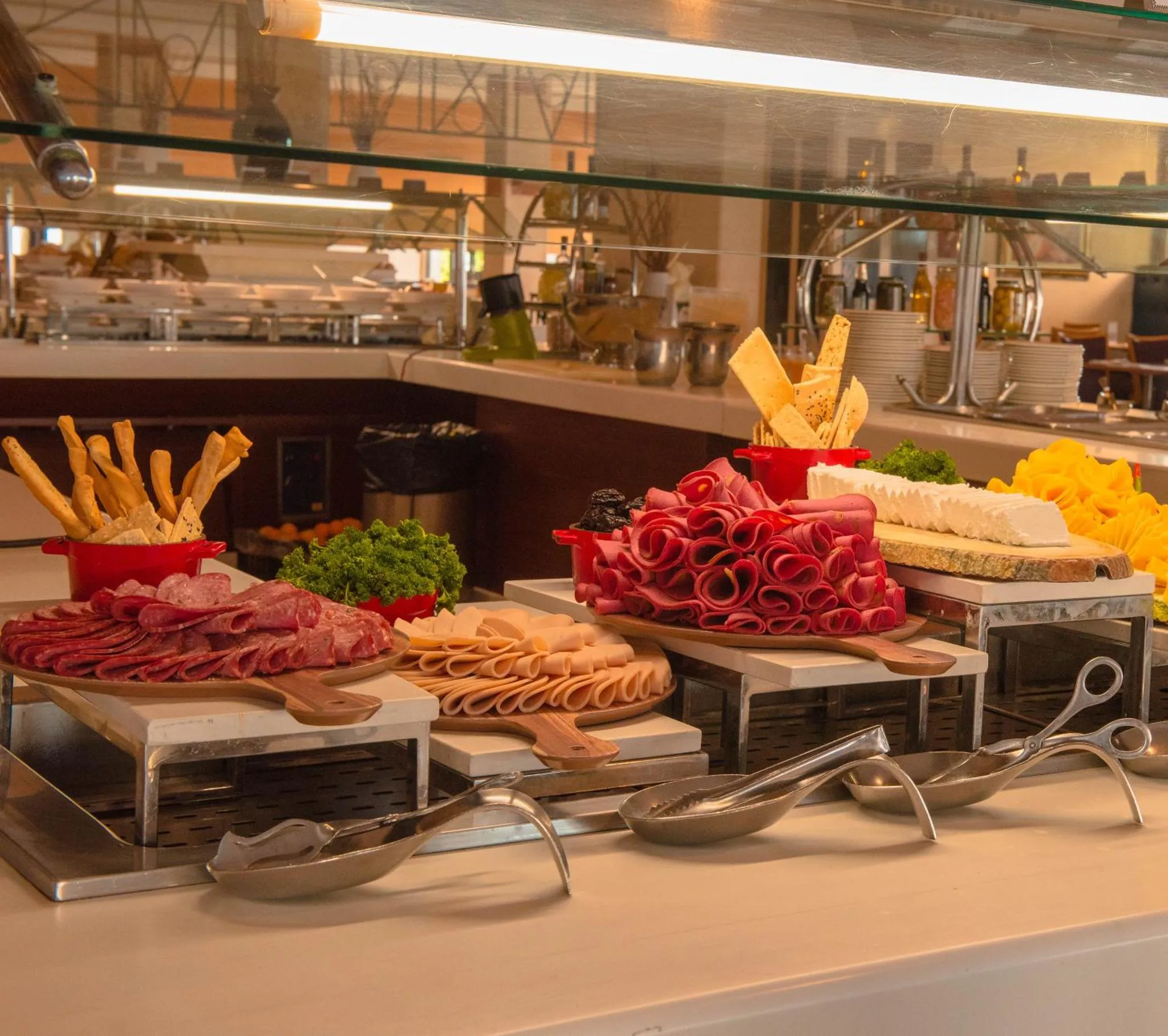 Présentation de charcuteries, fromages et crudités sur un buffet.