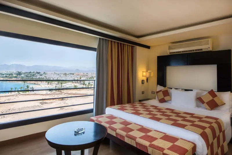 Chambre lumineuse avec un grand lit et vue sur la mer.