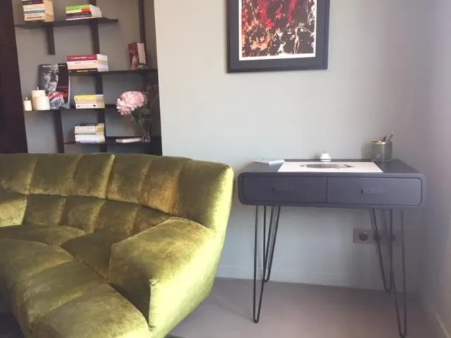 Un canapé vert et un bureau en bois sombre dans une pièce décorée.