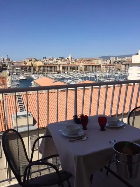Une table est dressée sur une terrasse avec vue sur la ville et le port.