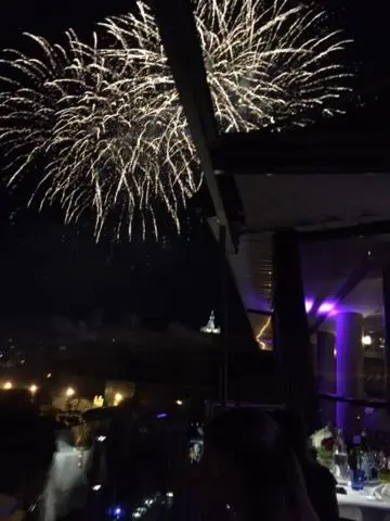 Feux d'artifice illuminant un ciel nocturne au-dessus d'une terrasse.