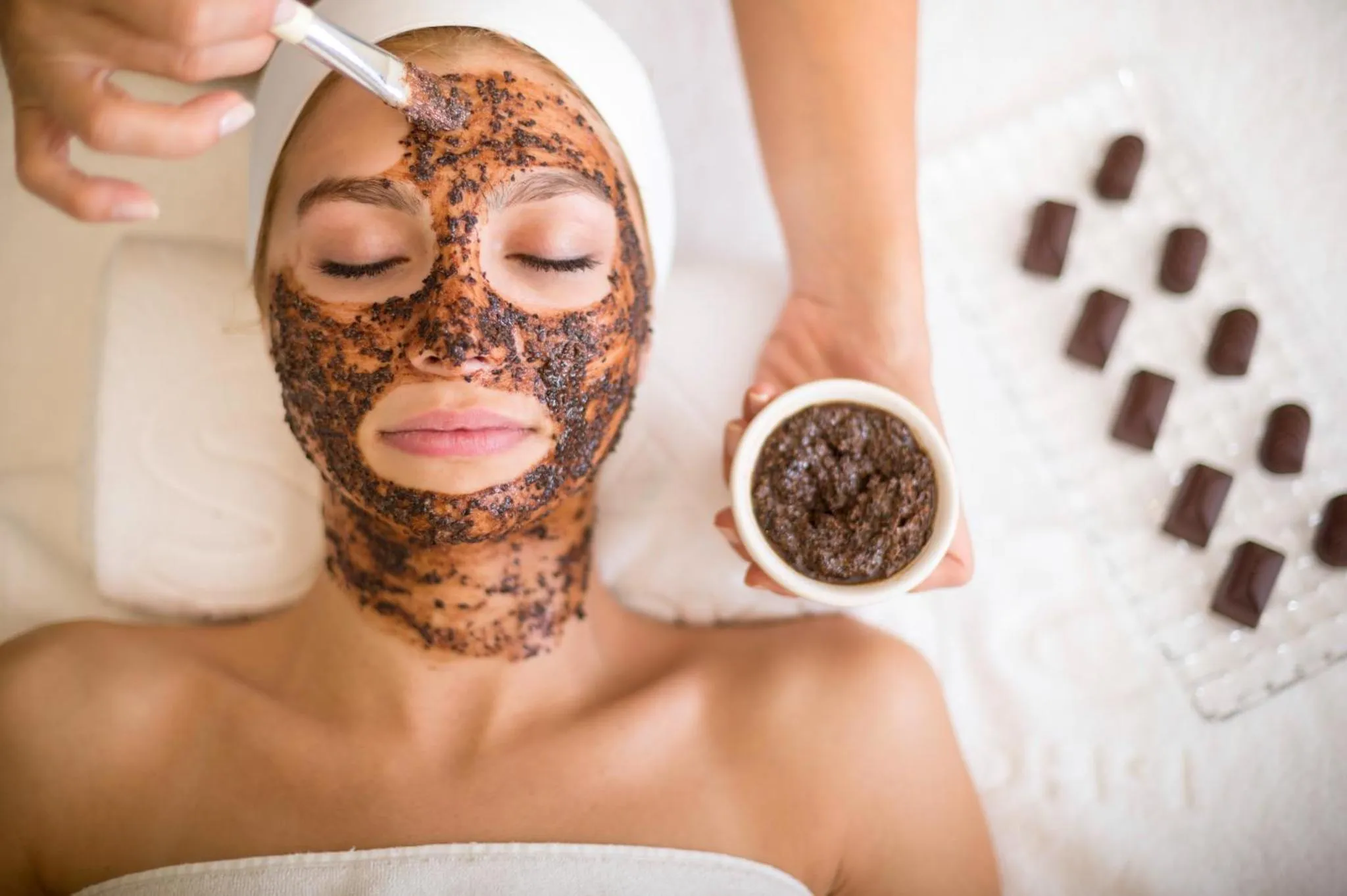 Une femme allongée reçoit un soin du visage au chocolat.