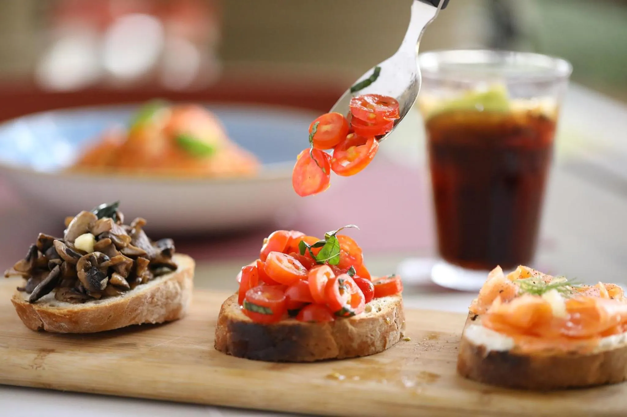 Assortiment de bruschettas garnies et boisson rafraîchissante sur une planche en bois.