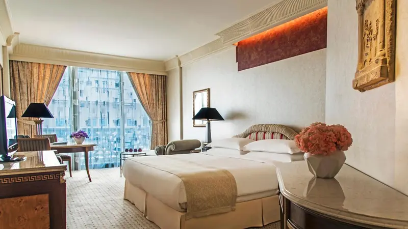 Chambre lumineuse avec un grand lit et une vue sur la ville.