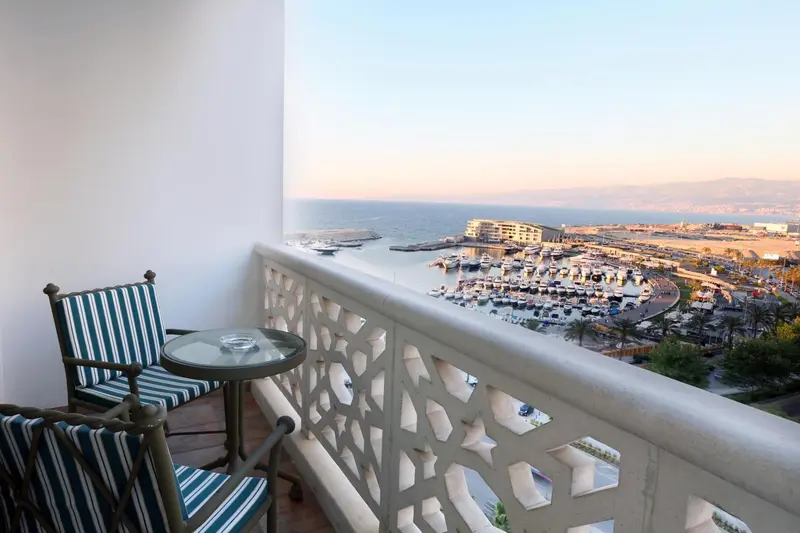 Balcon avec mobilier de jardin donnant sur un port de plaisance et la mer.