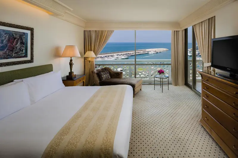 Chambre lumineuse avec un grand lit et une vue sur la mer.