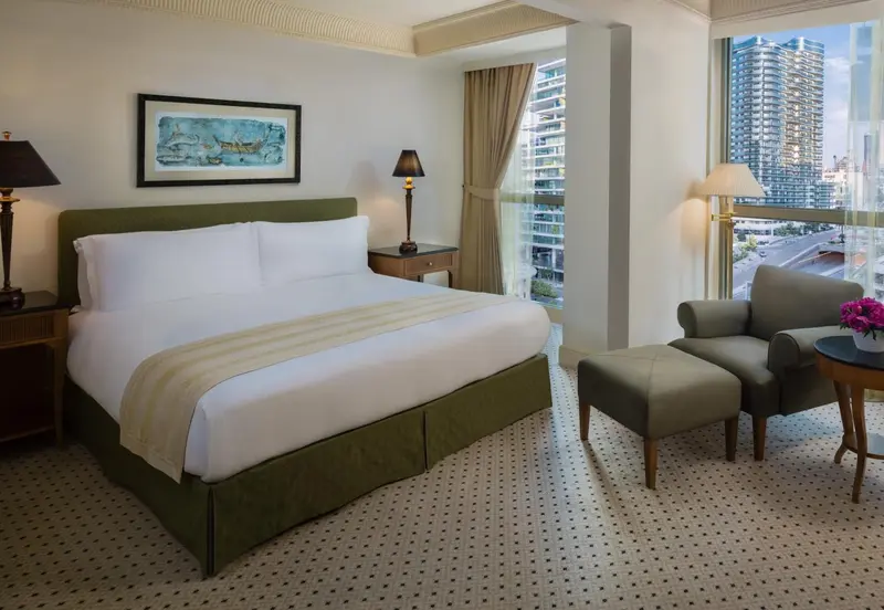 Une chambre lumineuse avec un grand lit et un coin salon près d'une fenêtre.