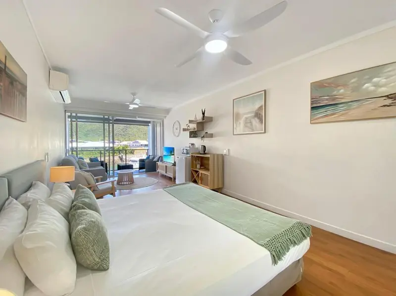 Une chambre lumineuse avec un grand lit et un canapé face à une baie vitrée.