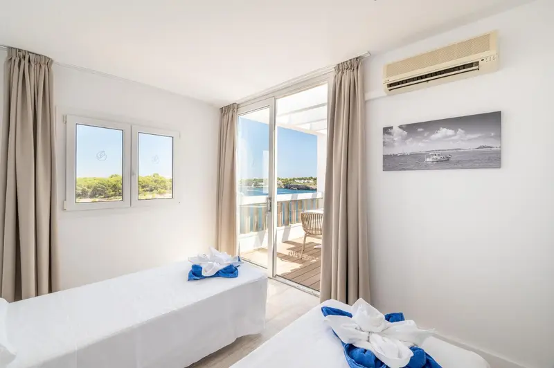 Chambre lumineuse avec vue sur un balcon et la mer.