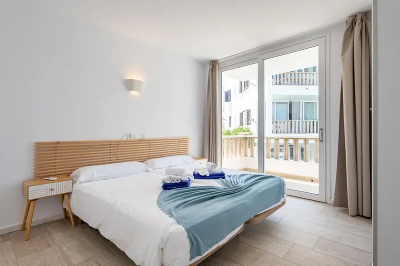 Une chambre lumineuse avec un lit double et un accès à un balcon.