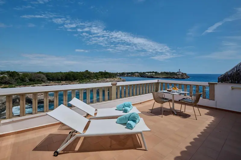 Terrasse avec chaises longues et table donnant sur la mer.