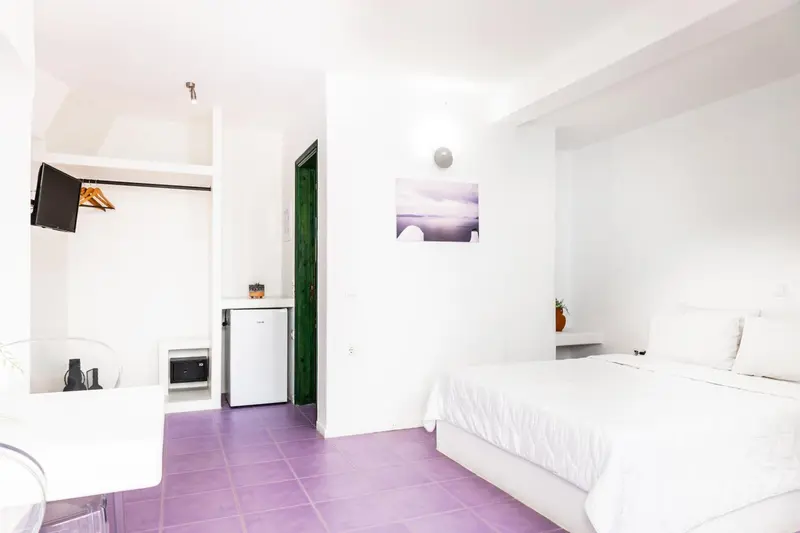 Une chambre lumineuse avec un lit et un coin cuisine.