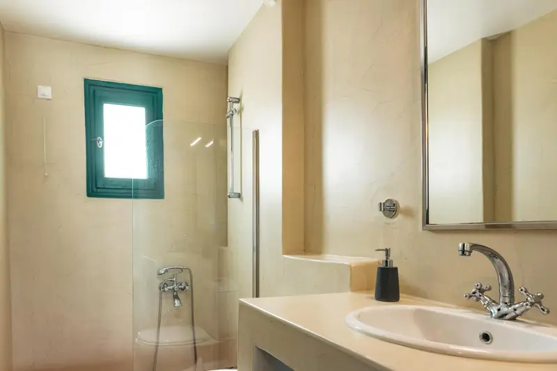 Une salle de bain lumineuse avec douche et lavabo.