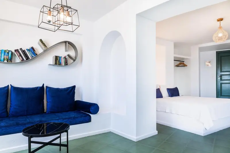Espace de vie intérieur avec canapé bleu et lit blanc.