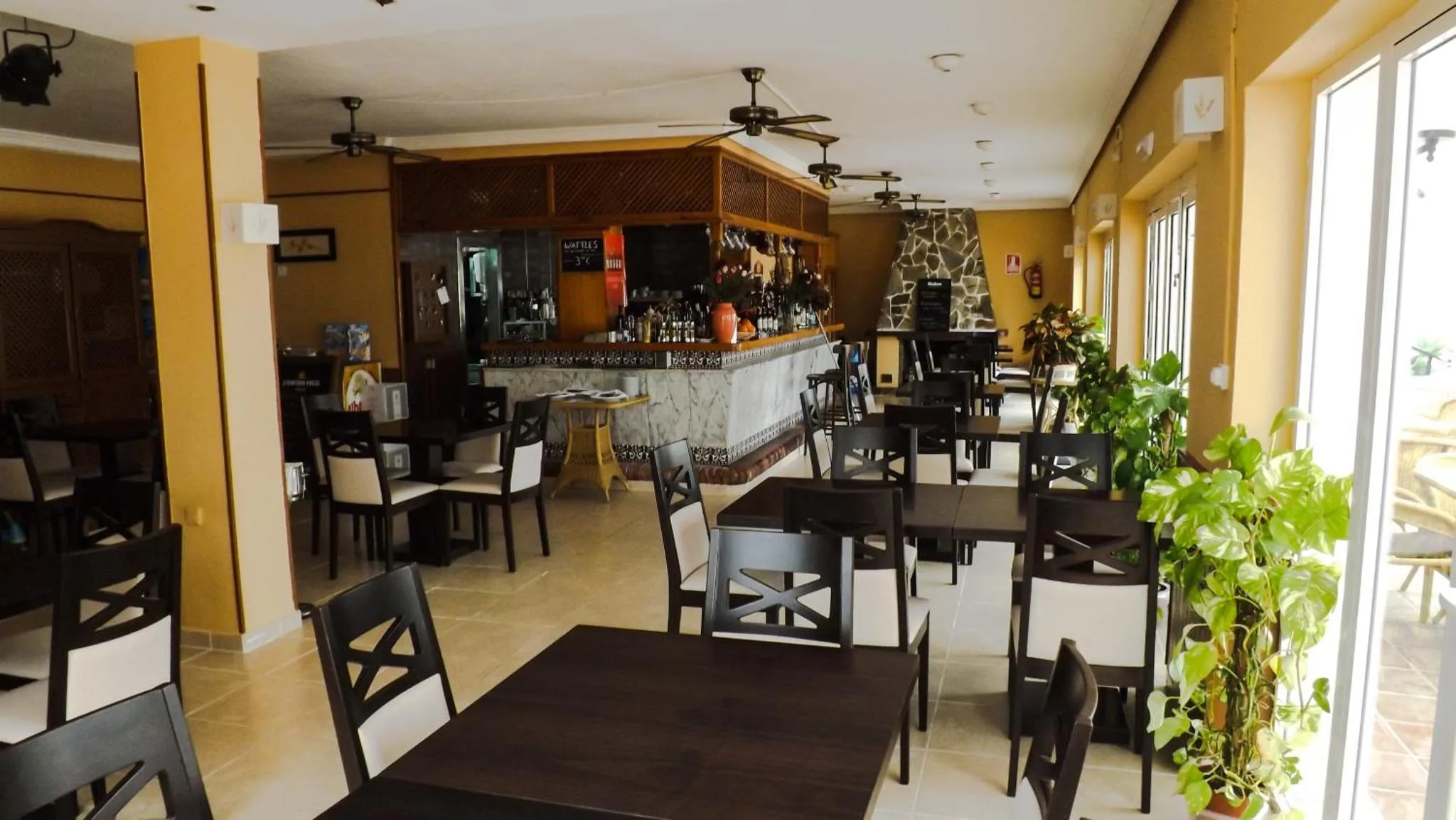 Une salle lumineuse avec un comptoir de bar et des tables à manger.
