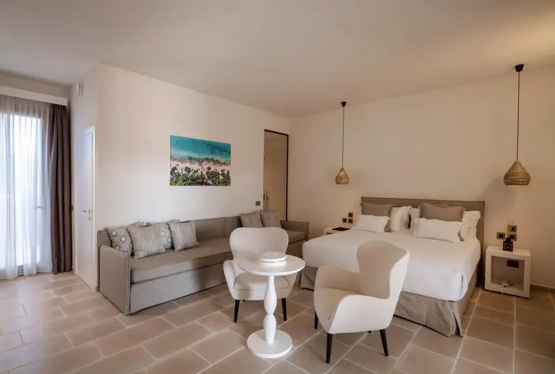 Une chambre lumineuse avec un coin salon et un lit double.