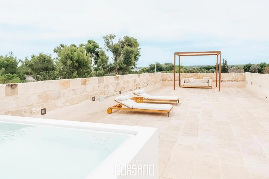 Terrasse aménagée avec transats et pergola, surplombant une piscine et un paysage verdoyant.
