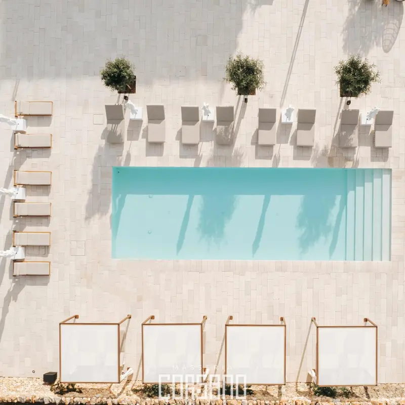 Transats alignés au bord d'une piscine rectangulaire turquoise.