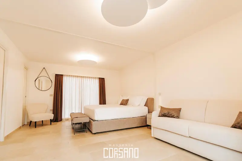 Une chambre lumineuse avec un grand lit et un coin salon.