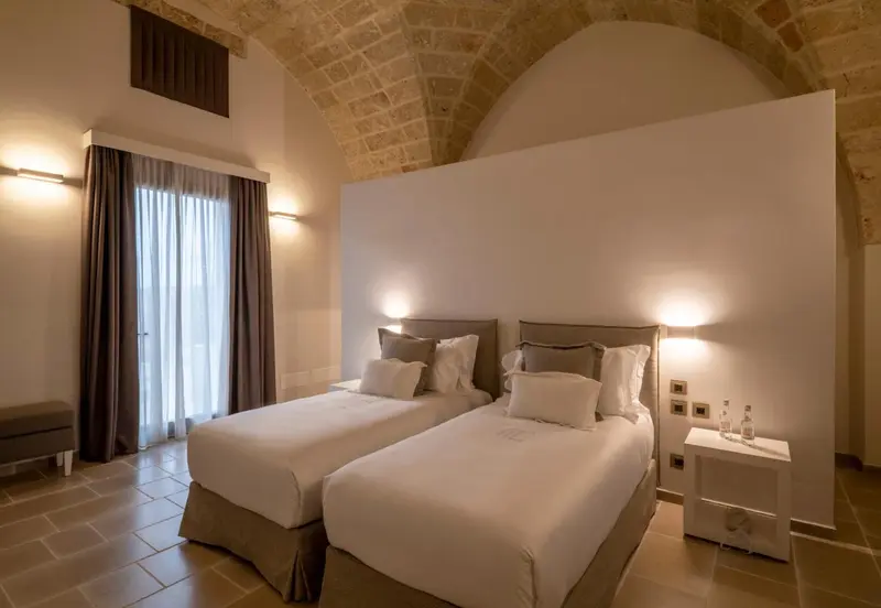 Chambre lumineuse avec deux lits simples et murs clairs.
