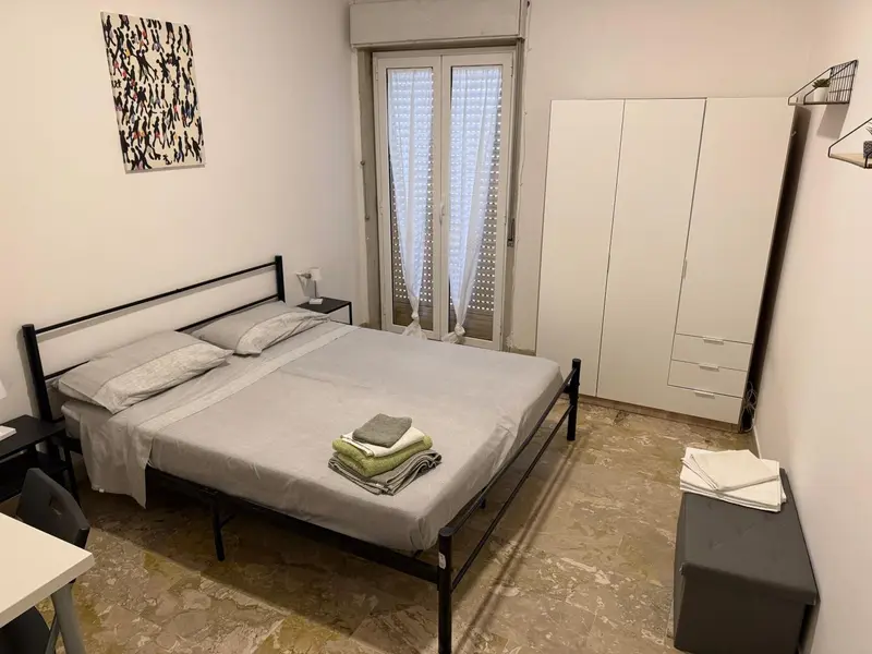 Une chambre avec un lit double et un accès à une terrasse par des portes-fenêtres.