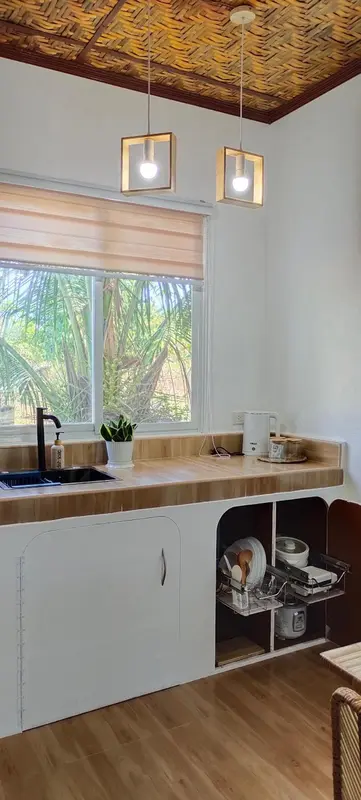 Une cuisine lumineuse avec un plan de travail en bois et des rangements blancs.