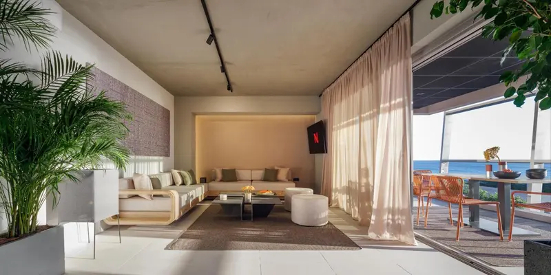 Espace de détente intérieur avec canapés et accès à une terrasse ensoleillée.