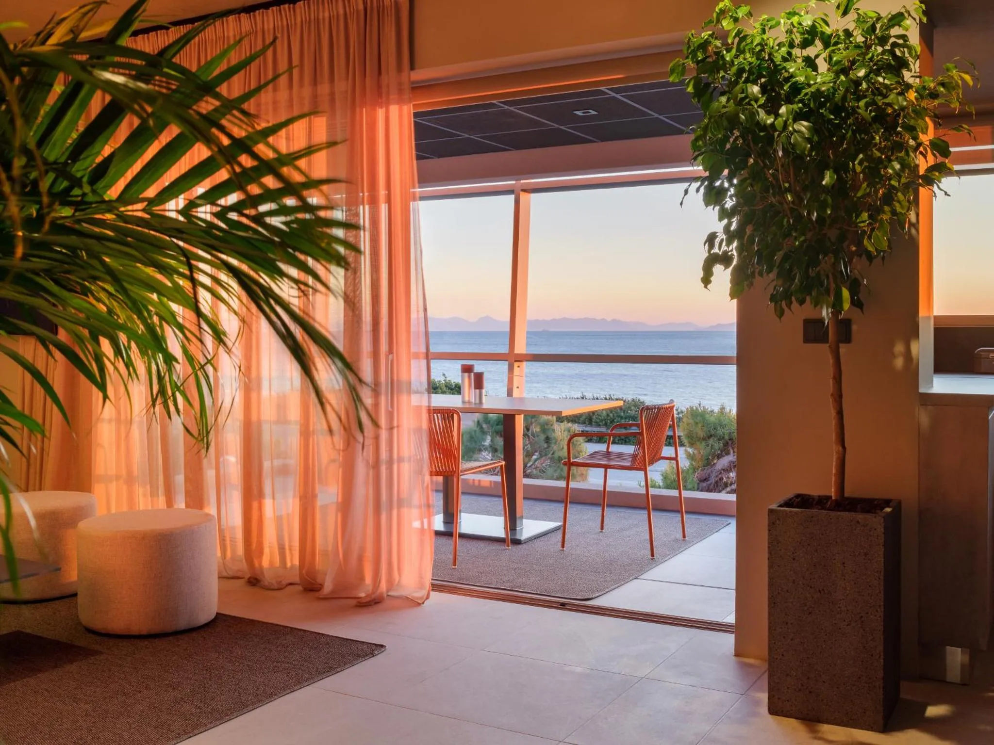 Une terrasse avec une table et des chaises offre une vue sur la mer au coucher du soleil.