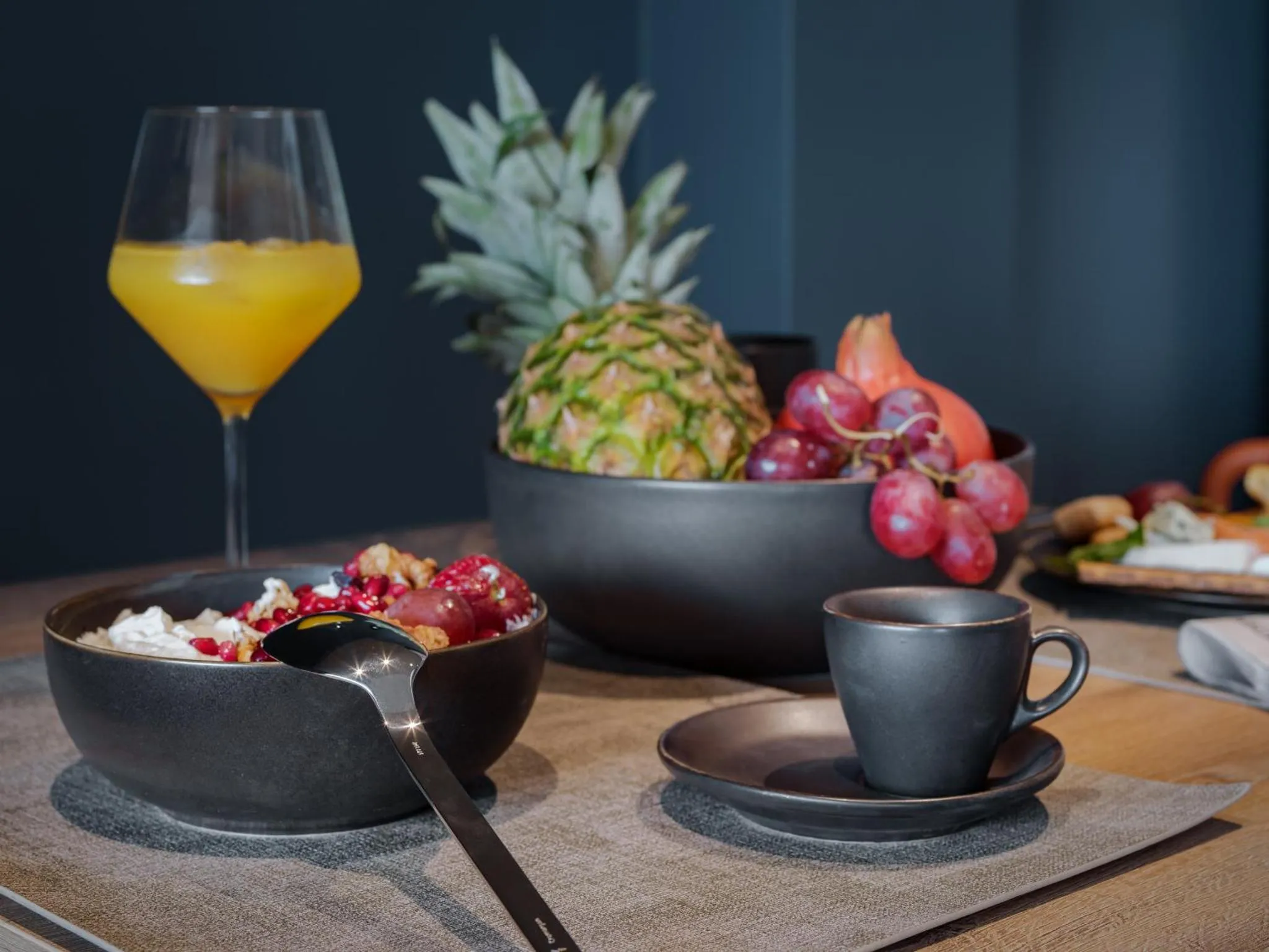 Nature morte avec un jus d'orange, un ananas, des fruits rouges et un bol de céréales.