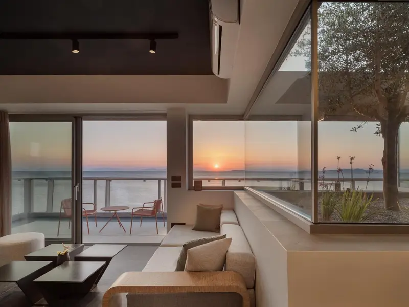 Un espace de vie lumineux s'ouvre sur une vue panoramique sur la mer au coucher du soleil.