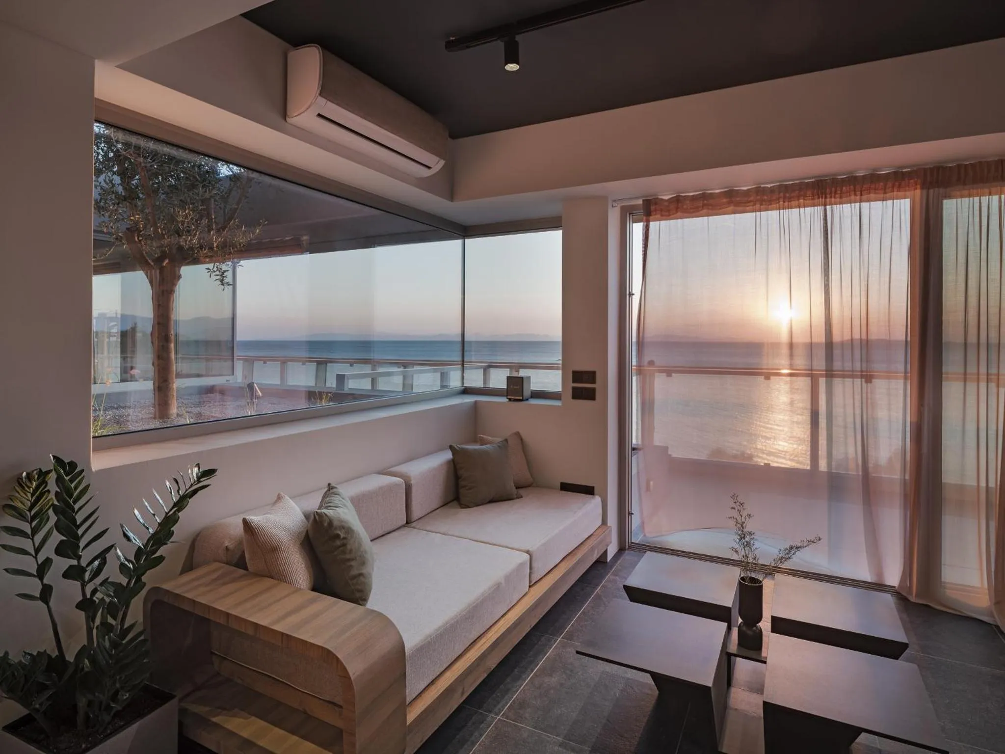 Espace de détente intérieur avec canapé et vue sur la mer au coucher du soleil.