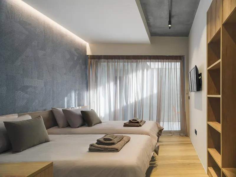 Une chambre moderne avec deux lits simples et une fenêtre drapée.
