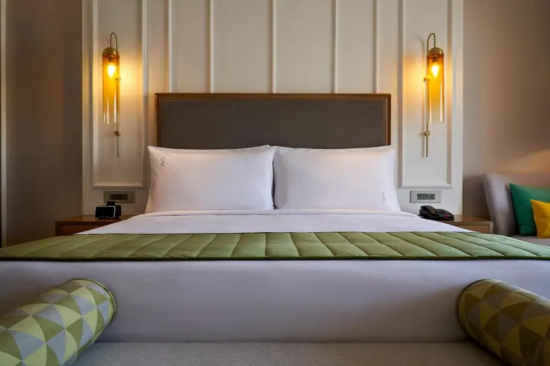 Un lit double avec une tête de lit rembourrée dans une chambre lumineuse.