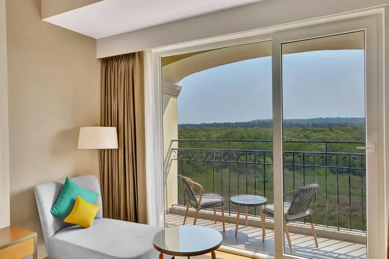 Une pièce lumineuse s'ouvre sur une vue verdoyante grâce à de larges baies vitrées et un balcon.