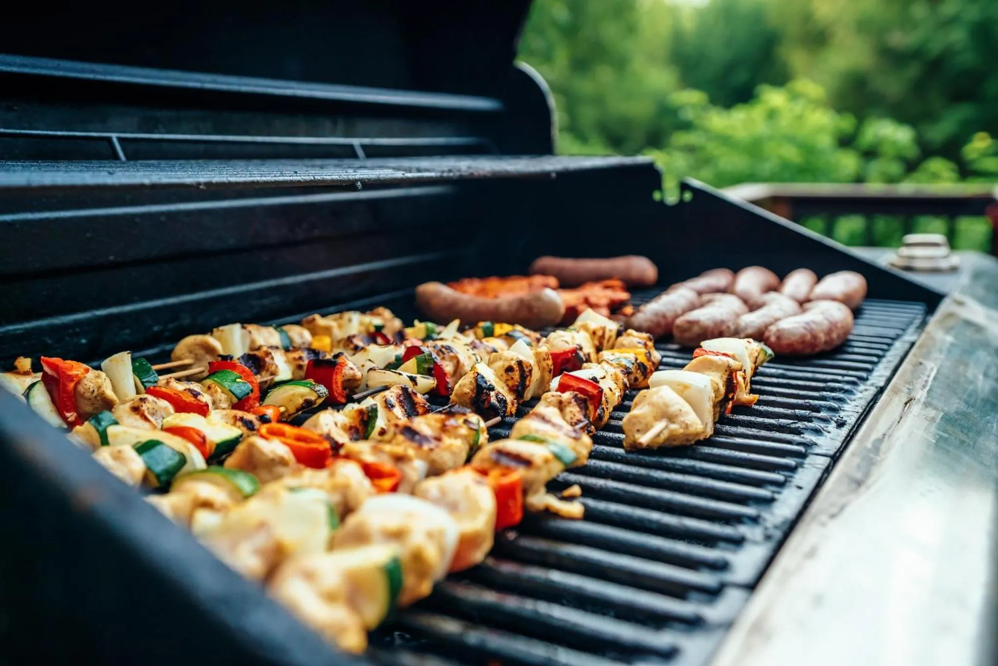 Des brochettes de légumes et de viande grillent sur un barbecue.