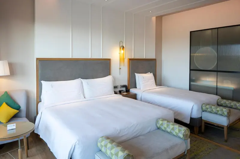 Une chambre lumineuse avec deux lits simples et un coin salon.