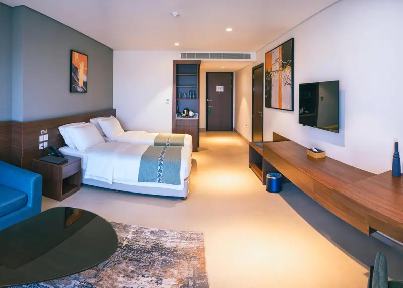 Chambre lumineuse avec deux lits et mobilier en bois.