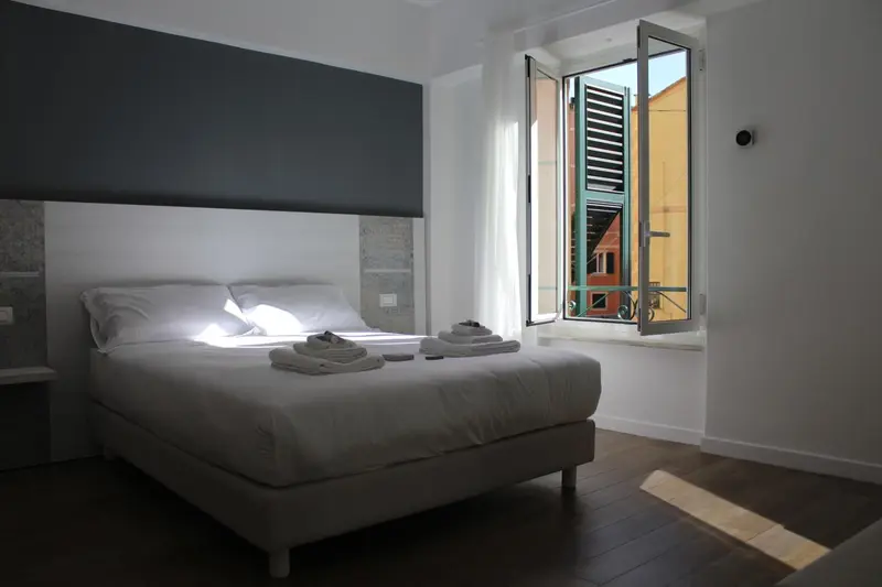 Une chambre lumineuse avec un grand lit et une fenêtre ouverte.
