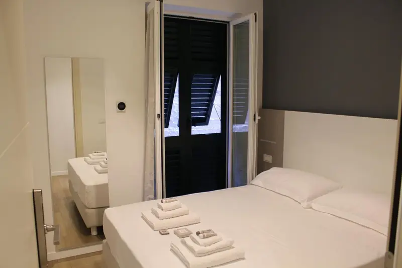 Une chambre lumineuse avec un lit fait et un accès à un balcon.