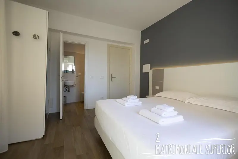 Une chambre lumineuse avec un grand lit recouvert d'une courtepointe blanche.