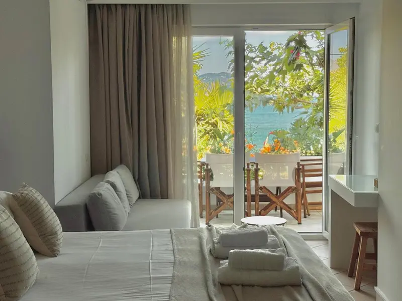 Une chambre lumineuse s'ouvre sur une terrasse avec vue sur la mer.