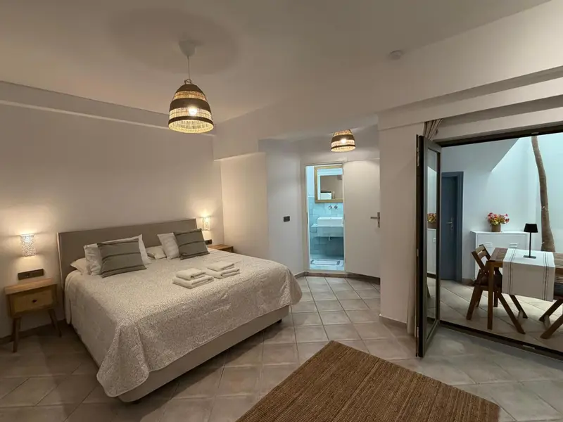 Chambre lumineuse avec un grand lit et accès à une terrasse.
