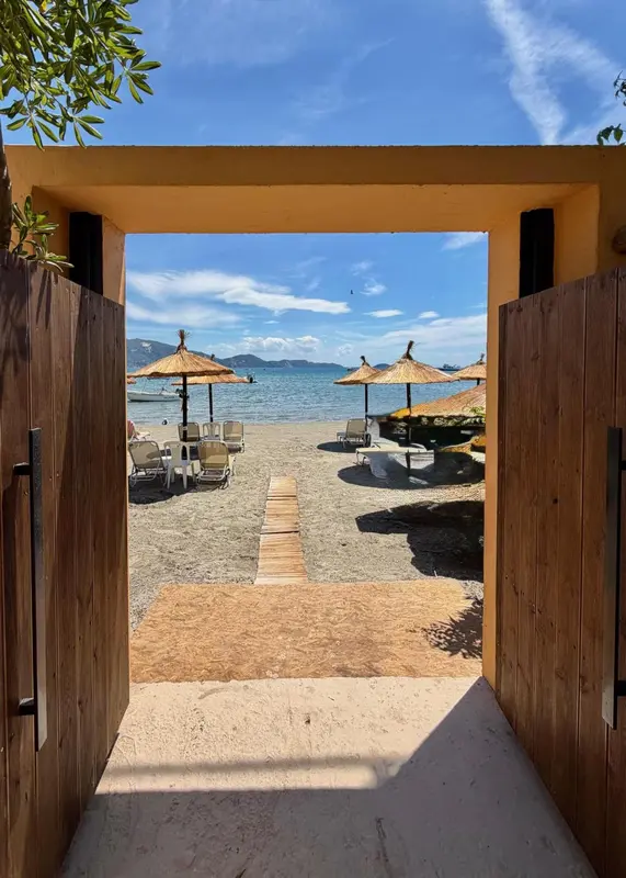 Vue sur une plage de sable fin avec des parasols et des transats.