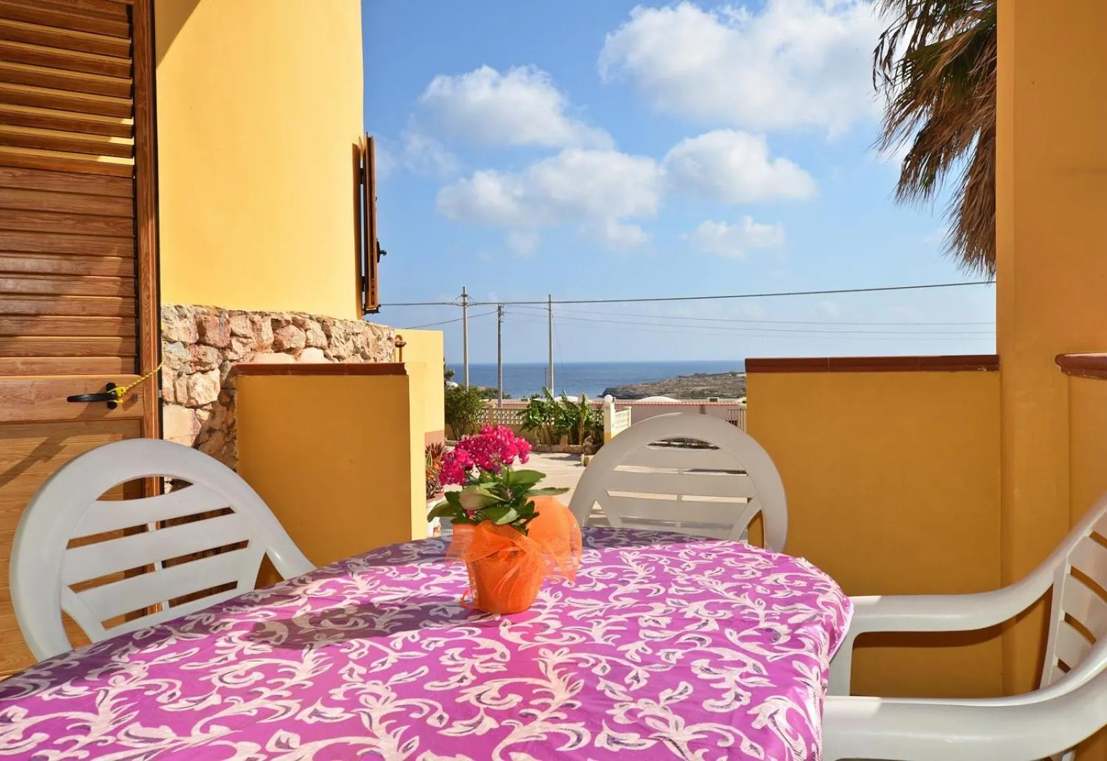 Une table et des chaises en plastique sur une terrasse ensoleillée avec vue sur la mer.