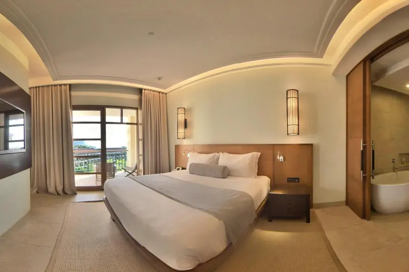 Une chambre lumineuse avec un grand lit et un accès à un balcon.