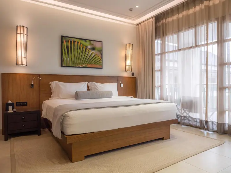 Une chambre lumineuse avec un grand lit et des rideaux clairs.